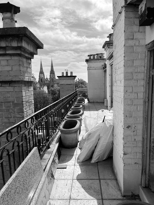 Coursive de la terrasse avant les travaux : dallage nu, pots vides et sacs de chantier